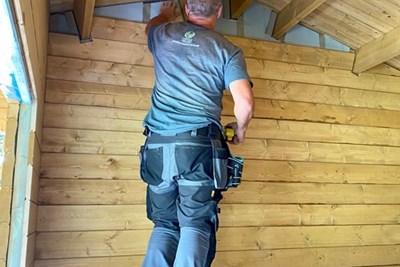 Man fitting internal wall with insulation